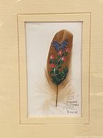 Front view of framed feather artwork showing painting, signature and date
