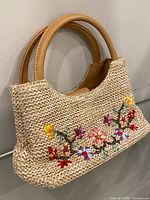 Front view of woven handbag showing embroidery and handles