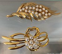 Leaf and bow Crown Trifari brooches front view