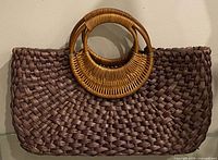 Front view of brown woven tote bag with round wooden handles
