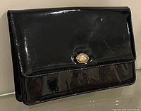 Front view of black patent Cabrelli purse with flap and clasp