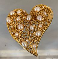 Front view of gold-tone filigree heart brooch with faux pearls and rhinestones
