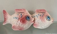 Front/side view of both porcelain fish piggy banks showing color, slots, overall condition