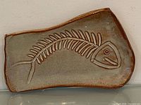 Full view of signed stoneware dish with fish skeleton design