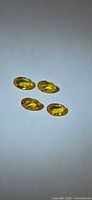 Four oval canary yellow sapphires on neutral background