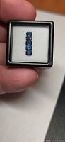 Five emerald-cut blue sapphires in display case