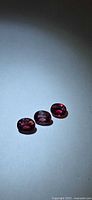 Three oval hot pink sapphires on neutral background