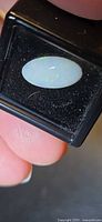 Front view of oval white opal cabochon in gem case