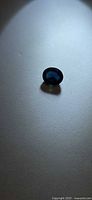 Loose oval blue sapphire on flat surface under spotlight