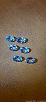 Six oval blue gemstones on surface