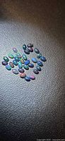 Group of small oval black opal cabochons on textured black surface