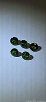 Five round green chrome diopside stones on white background
