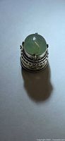Round green jadeite cabochon in metal holder, top view