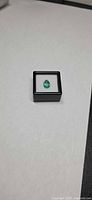 Pear-cut emerald in gem box, overview