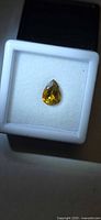Pear-cut vivid yellow tourmaline in display case