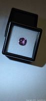 Loose pink cushion-cut spinel displayed in plastic case