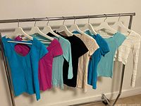 Eight assorted tops hung on rack front view