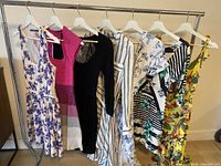 Seven dresses hanging on rolling rack front view