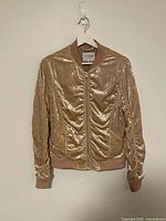 Front view of gold Guess velour bomber jacket on hanger