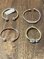 Four cuff bracelets arranged on wood surface