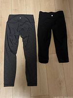 Both pairs of leggings laid flat, showing front and waistband logos