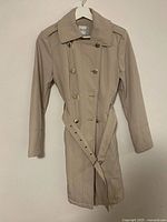 Front view of beige Guess trench coat on hanger showing full length, belt, buttons