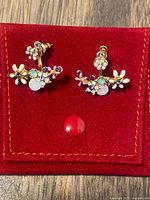 Front view of both ear jacket earrings in red holder showing floral crystal design