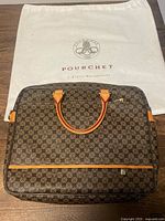 Front view of Pourchet monogram canvas laptop bag with leather handles and dust bag