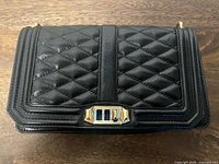 Front view showing black chevron-quilted leather, gold-tone clasp, overall condition