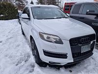 Front and driver-side view showing white body, black grille, black rims, snow-covered surroundings