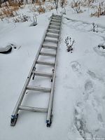 Full length view of the 28' aluminum extension ladder resting on snow