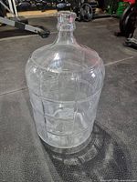 Full view of clear glass carboy on gym floor