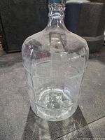 Full view of clear glass carboy standing upright