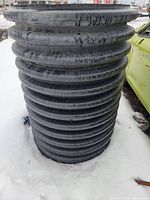 Full vertical view of black corrugated culvert standing in snow