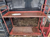 Full view of red metal two-shelf cart on wheels