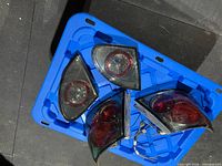Four Toyota Corolla taillight assemblies on blue tray, showing lenses and wiring