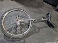 Full view of unicycle showing frame, wheel, tire, pedals, and saddle