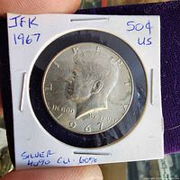 Obverse view of 1967 Kennedy half dollar in cardboard flip showing handwritten details