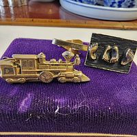 Both tie clips on display, locomotive and footprint designs visible