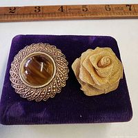 Front view of both brooches on velvet pad with ruler for scale