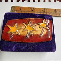 Front view of enamel brooch with ruler for scale