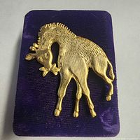 Front view of gold-tone giraffe brooch on display pad