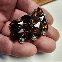 Front view of brooch held in hand showing stone colors and overall design