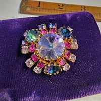 Front view of brooch on purple cloth showing multicolour rhinestones