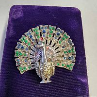 Front view of peacock brooch on velvet pad
