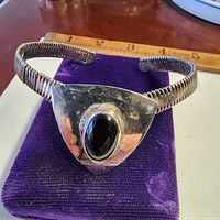 Front view of silver-tone cuff bracelet showing black onyx stone and coiled band