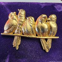 Front view of gold-tone five-bird brooch