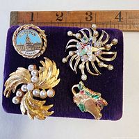 Four brooches on velvet pad with ruler