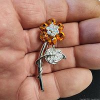 Front view showing amber rhinestone petals, clear rhinestone center and silver-tone leaf