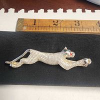 Front view of silver-tone panther brooch showing texture and red eyes